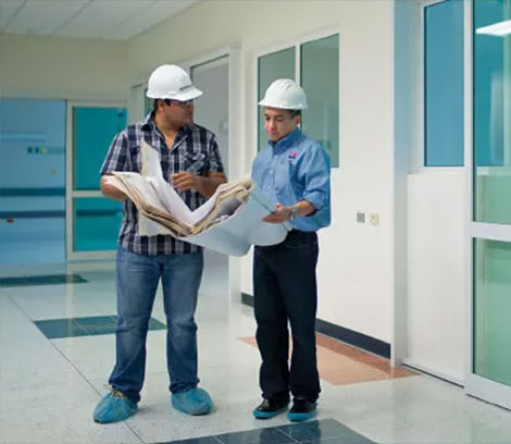 two men in hard hats standing in a hallway