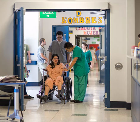 a woman in a wheelchair being helped out of a hallway